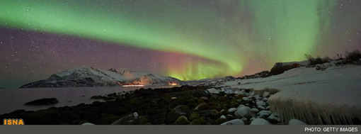 تصویر بازتاب شکل خط ساحلی یخزده در نور گسترده شفق قطبی از مایک کاری