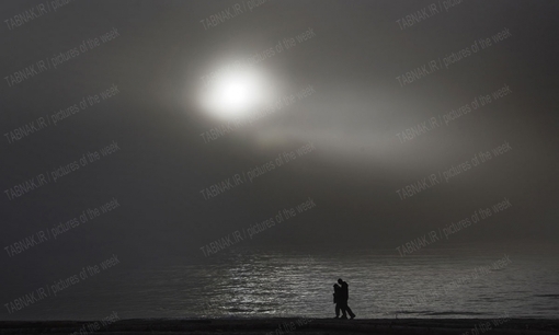 قدم زدن زن و شوهری در هنگامه غروب خورشید در ساحل اسکله ای در غرب ونکور-
REUTERS/Andy Clark
