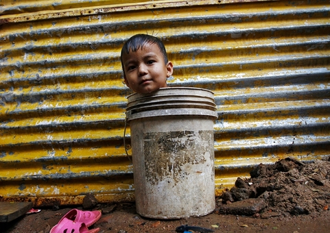 کودکی در یکی از شهرهای هند، درون سطلی نشسته و در انتظار رسیدن مادرش برای استحمام است REUTERS/Babu
