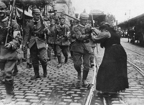 سال ۱۹۱۴ - پیاده نظام گارد پروس در حال ترک برلین، آلمان، به سمت خط مقدم جبهه. دختران و زنان در طول راه به  بدرقه آنها رفته و دست گل به سربازان اهدا می کنند