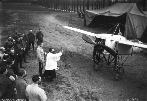 سربازان فرانسوی در کنار کشیش برای پرواز برکت آمیز هواپیمای جدید دعا می کنند در سال ۱۹۱۵