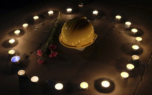 کلاه ایمنی یک معدنچی توسط معترضان به کوتاهی دولت ترکیه در برقراری امنیت جانی کارگران معدن پس از حادثه مرگبار انفجار معدن در میان شمعهایی که به یادبود مرگ دلخراش کارگران روشن شده قرار گرفته است/REUTERS/Yagiz Karahan