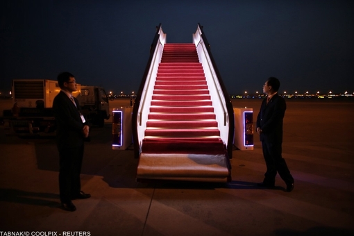 محافظان و نیروهای استقبال از حسن روحانی در فرودگاه بین المللی پادونگ در چین، خود را آماده نشستن هواپیمای رئیس جمهور ایران می کنند.