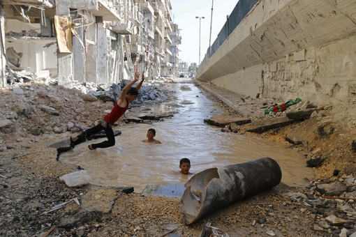 فارغ از جنگ و خشونت و بمب، کودکان سوریه ای در شهر حلب از آب تنی در یک حوضچه خیابانی لذت می برند. این حوضچه از حمله هوایی ارتش سوریه بر علیه تروریستهایی که در میان مردم اختفا کرده اند بوجود آمده است/Reuters 