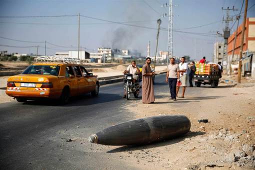 نوار غزه ساعاتی پس از برقراری آتش بس و بمب عمل نکرده رژیم صهیونیستی در جاده که ممکن است هر لحظه فلسطینیان را به کام مرگ فرو ببرد./Reuters 