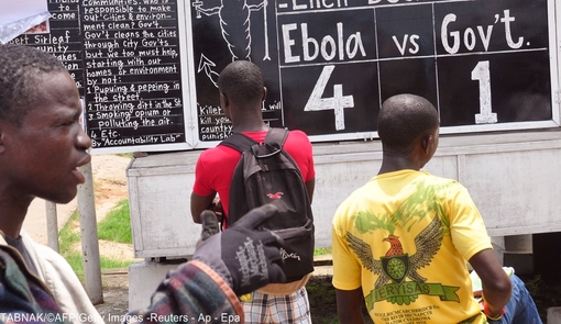 مطالبی در خصوص ابولا بر روی تخته نوشته شده و رهگذران در لیبریا آنرا مشاهده می کنند