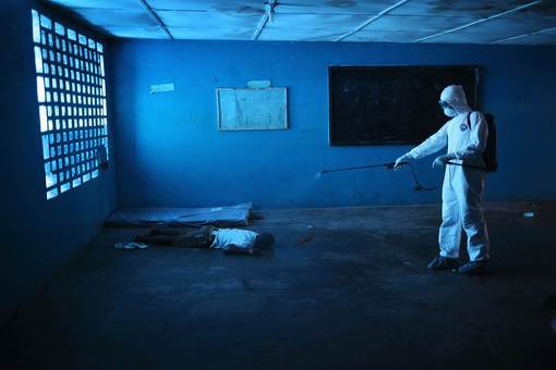 فاجعه جانباختن بیماران مبتلا به ویروس مهلک ابولا در مونرویا، لیبریا و کارمند وزارت بهداشت که وارد کلاس درس شده و جسد دانش آموز جانباخته را ضد عفونی می کند./Getty Images