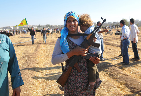 زن خرسند کرد سوری از پشت حصارهای مرزی ترکیه، توانسته یک سلاح کلاشنیکف را از هموطن کرد خود در آنسوی مرز(ترکیه) تحویل بگیرد تا در موقع لزوم از خود و فرزندش دفاع کند./Getty Images