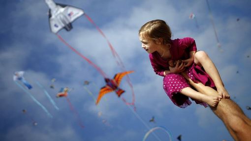 دخترکی بر روی پای پدرش نشسته و پرواز بادبادکها در جریان جشنواره بادبادکها در ساحل کالیفرنیا را تماشا می کند./REUTERS
