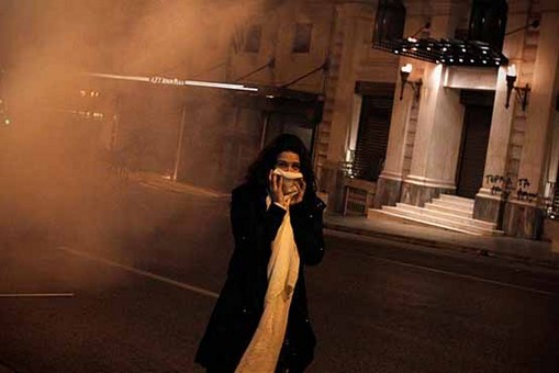 یک زن برای در امان ماندن از گاز اشک آور صورت خود را پوشانده است.