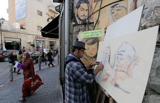 یک نقاش در حال ترسیم تصویر رهبرفقید فلسطینیان یاسر عرفات و شیخ احمد یاسین در کرانه باختری در غرب رام الله &ndash; اخیراً نتیجه تحقیقاتِ علت مرگ عرفات مشخص شده، وی احتمالاً با مواد رادیو اکتیو پلونیوم مسموم گردیده و از پای درآمده است.
 REUTERS/Ammar Awad
