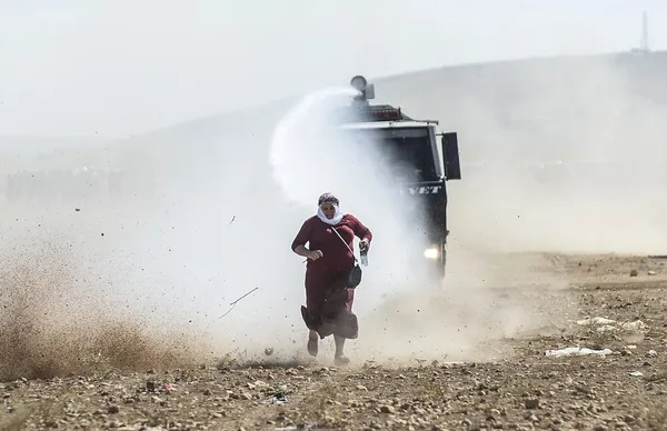 فرار زن پناهنده کرد سوری از آب پاش پلیس مرزی استان شانلی&zwnj; اورفه ترکیه./AFP