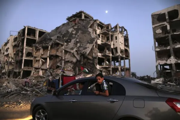 کودک فلسطینی در شهر بیت لاهیا سرش را از پنجره خودرو بیرون آورده و از کنار آوار وحشتناک خانه ها که توسط صهیونیستها به این روز افتاده عبور می کند.
