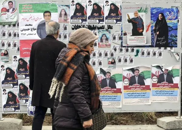 تهران، ایران ـ مردم در کنار پوسترهای نامزدهای شرکت کننده در انتخابات پارلمانی آینده قدم می زنند. 