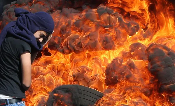 لحظه انفجار لاستیکها و پوشش صورت یک جوان فلسطینی از ترس آسیب دیدگی در مناطق درگیری فلسطینیان با پلیس رژیم صهیونیستی./AFP
